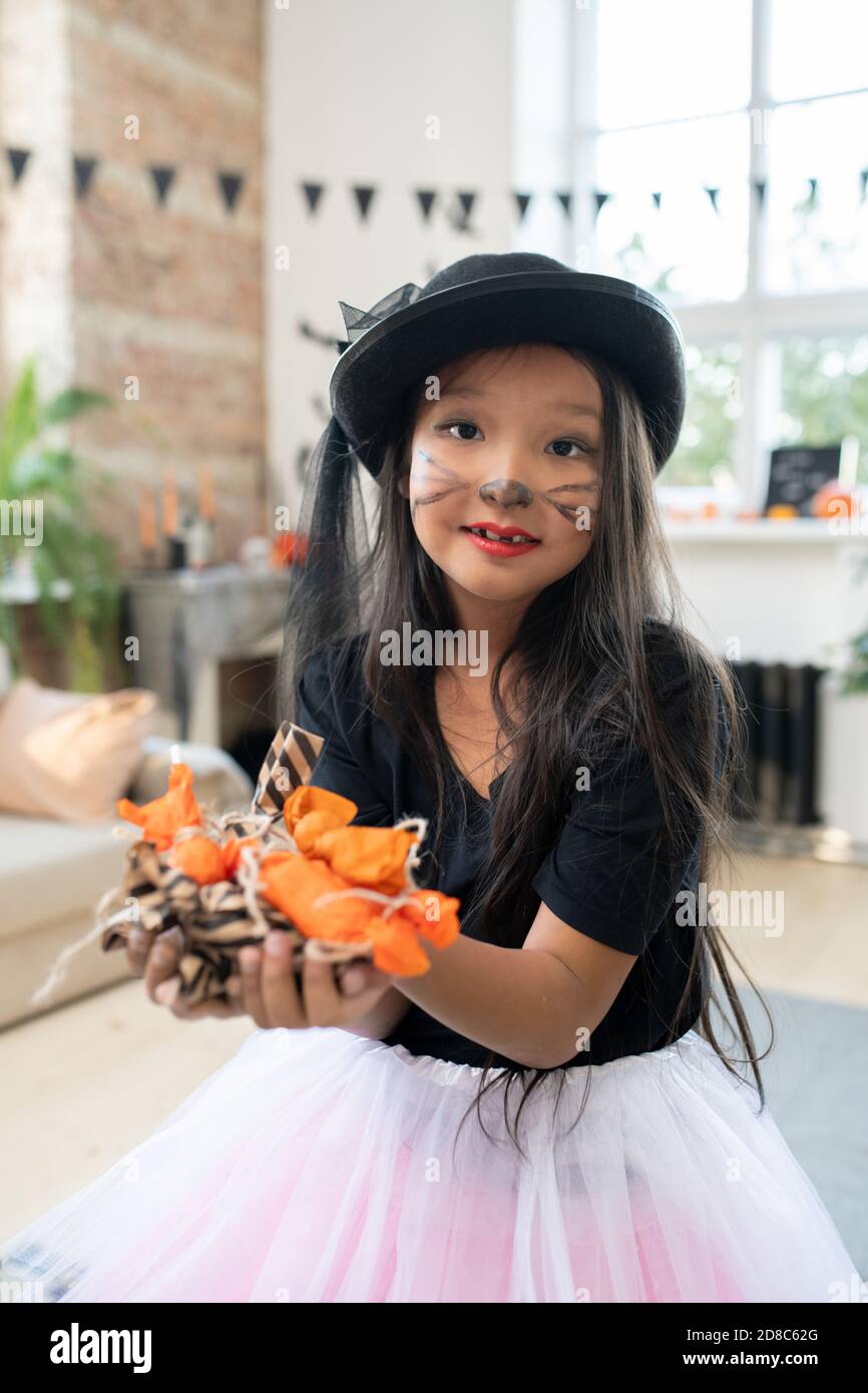 Portrait of content schöne asiatische Mädchen mit Kitty Make-up tragen Schwarzer Hut mit Haufen Halloween Süßigkeiten Stockfoto