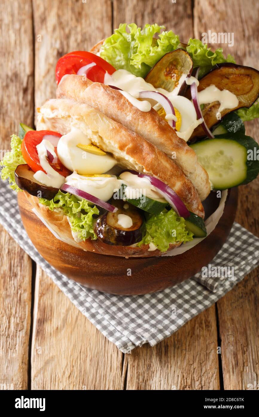 Israelische Fast-Food-Sabich-Sandwich mit Gemüse, Eier und Tahini Nahaufnahme auf dem Tisch. Vertikal Stockfoto