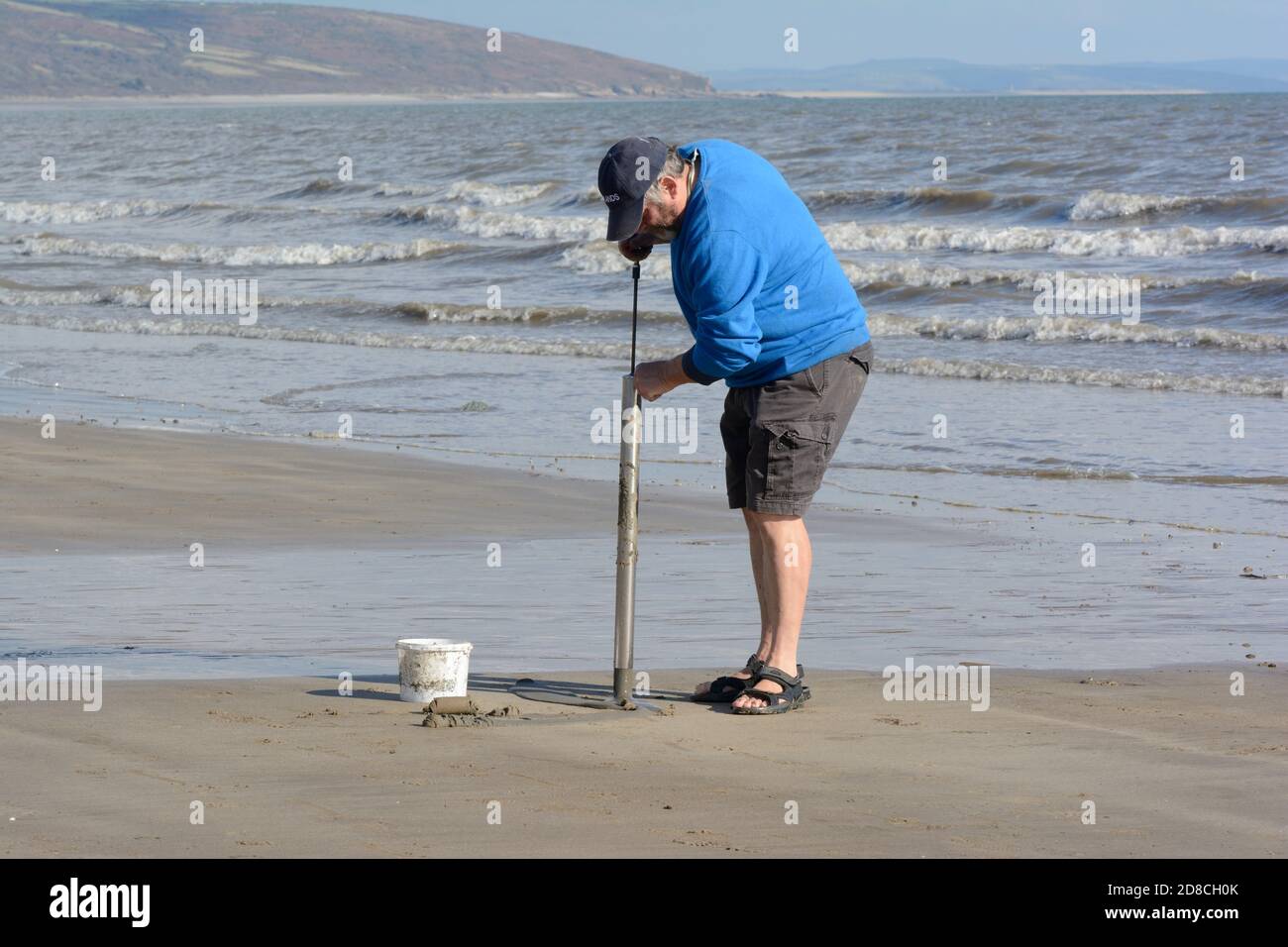 Mann mit einem Seefischen Köder Pumpe, um Lugworm zu finden Wisemans Bridge Beach Carmarthenshire Wales Großbritannien Stockfoto