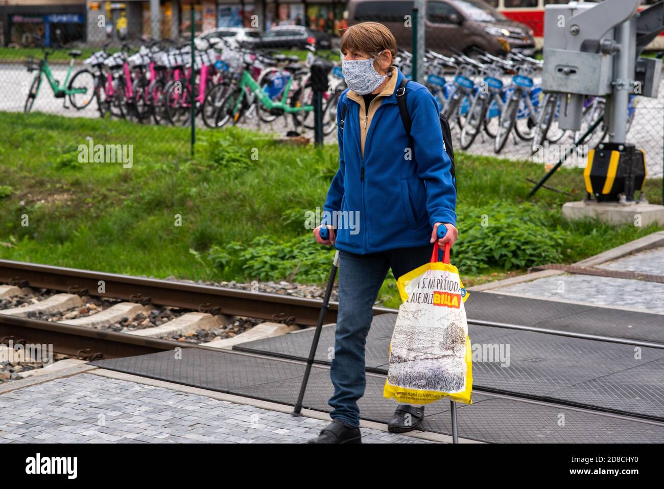 Alter Mann mit Maske und Spazierstock überquert den Zug Titel in Prag Stockfoto