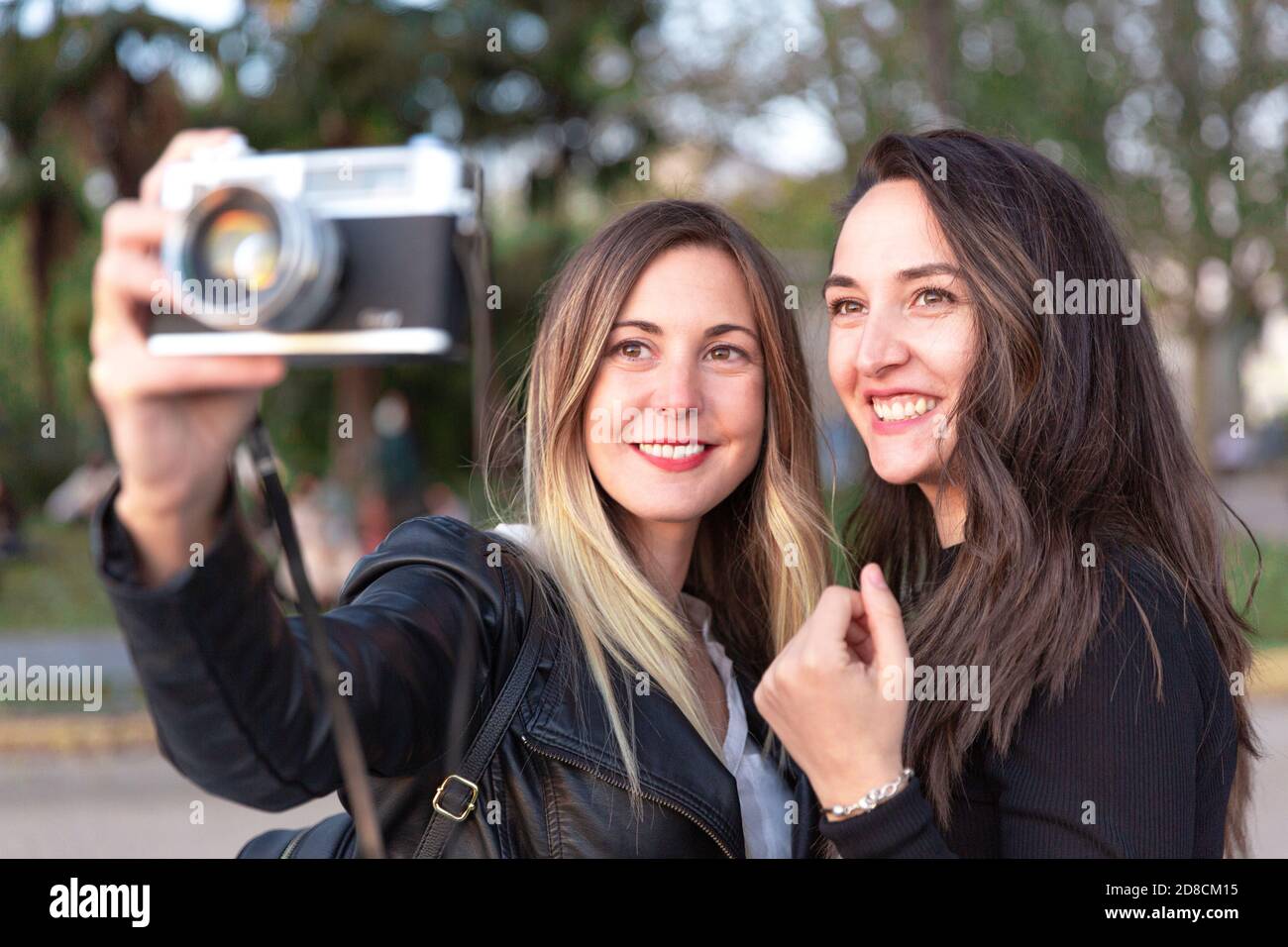 Nahaufnahme von zwei lächelnden Frauen mit einer analogen Kamera in den Händen. Stockfoto
