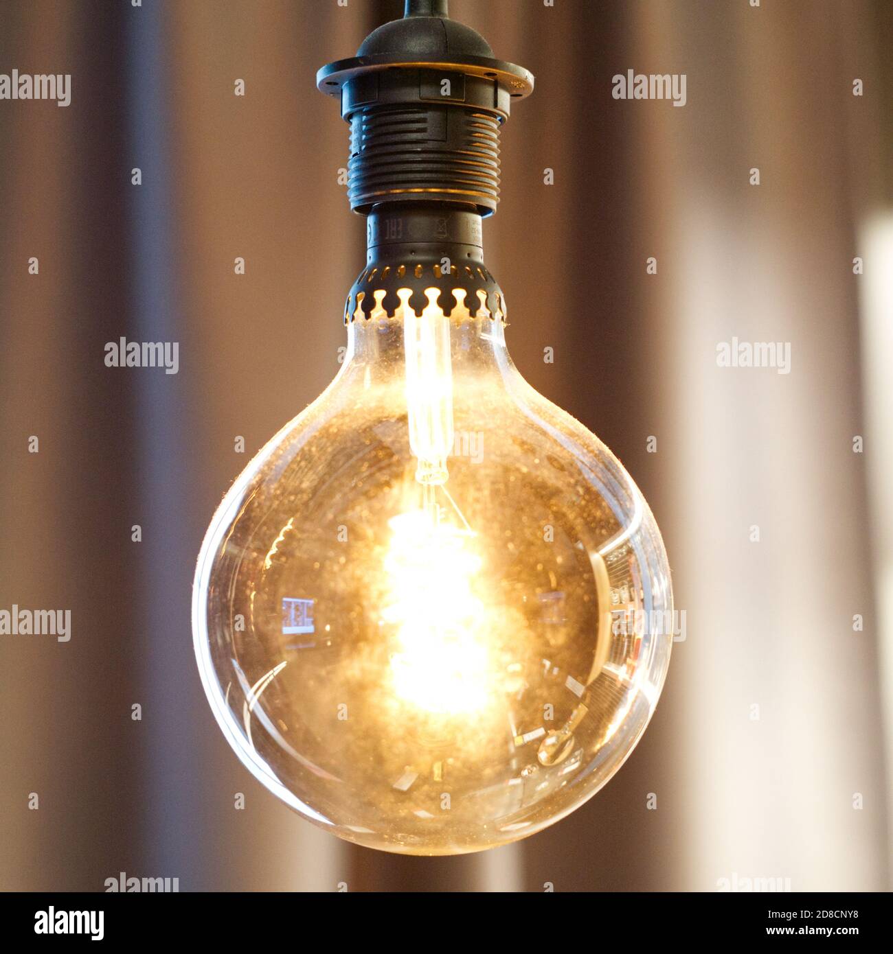 Runde Glühlampe auf braunem unscharfem Hintergrund Stockfoto