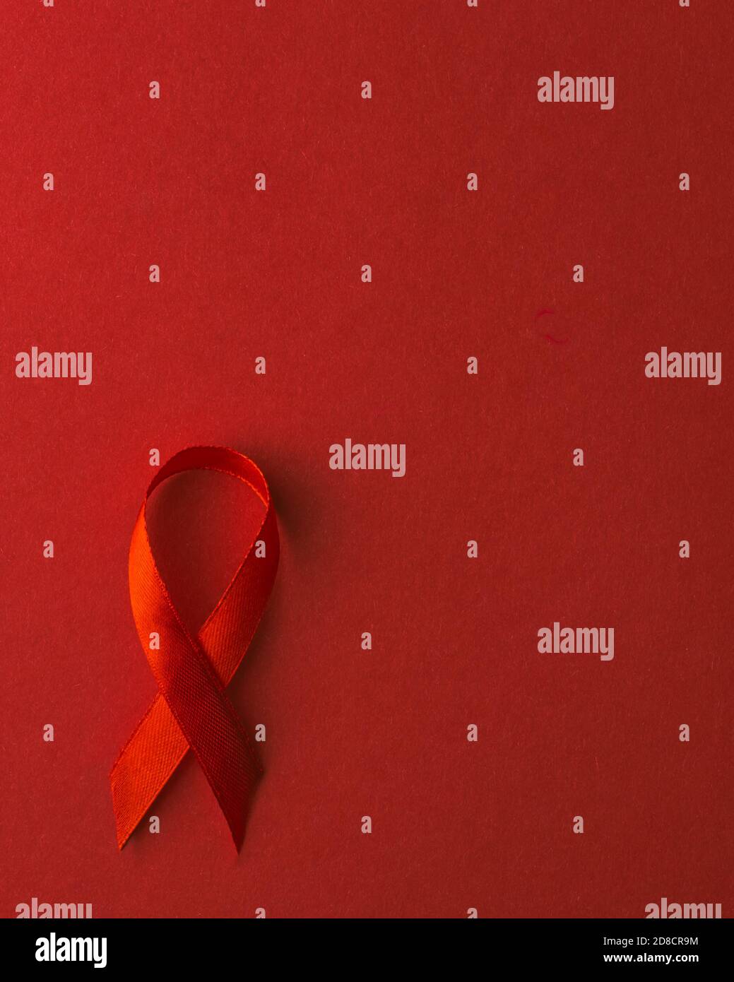 Rotes Schleife Symbol HIV, AIDS Krebs Bewusstsein mit Schatten, Studio-Aufnahme isoliert auf rotem Hintergrund, Gesundheitsmedizin Konzept, Welt AIDS Tag Stockfoto