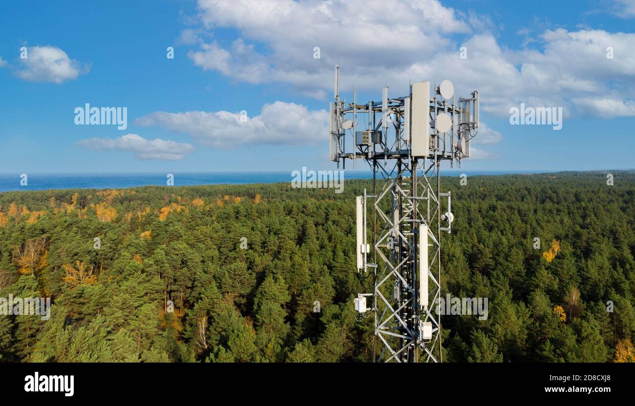Telekommunikationsturm mit Antennen für 5g-Netz auf Wald und blauer Himmel Hintergrund. Mobile Internet-Übertragung Stockfoto