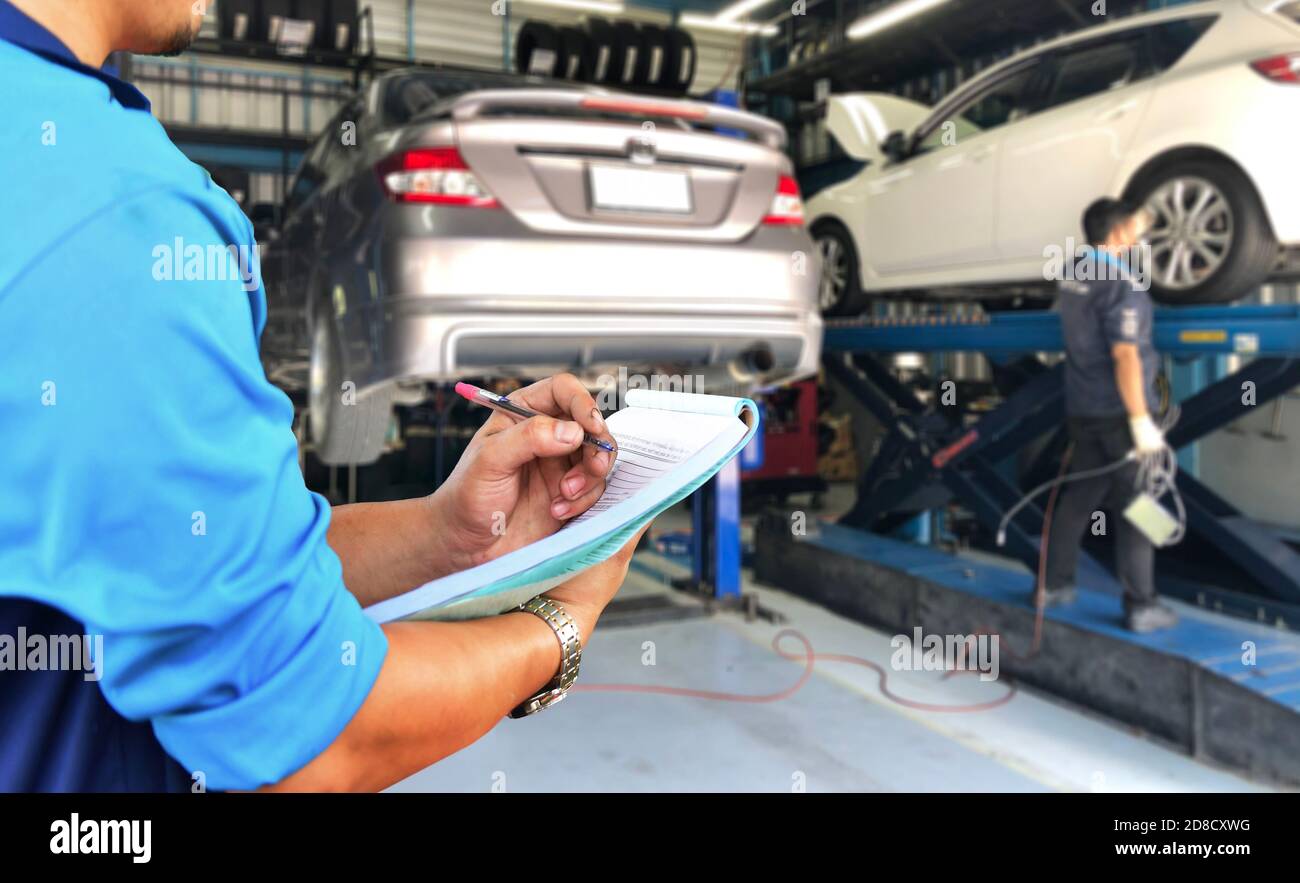 Mechaniker prüft die Motorreparaturliste in der Garage. Stockfoto