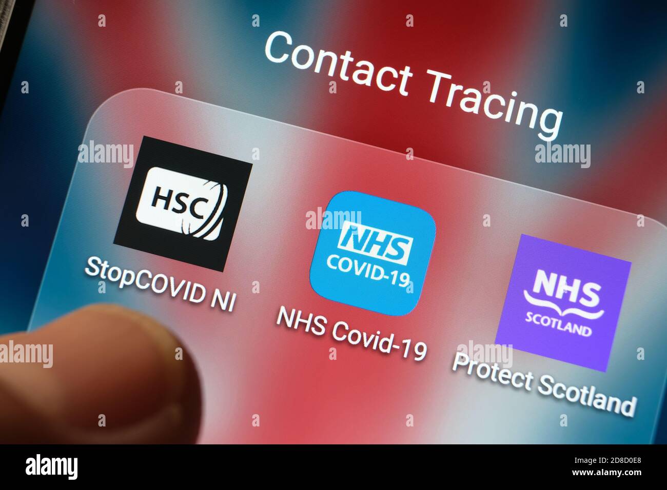 Die britische NHS COVID-19-App und andere Apps zur Kontaktverfolgung, die auf einem Bildschirm angezeigt werden und mit verschwommenen Fingerspitzen auf sie zeigen. Stockfoto