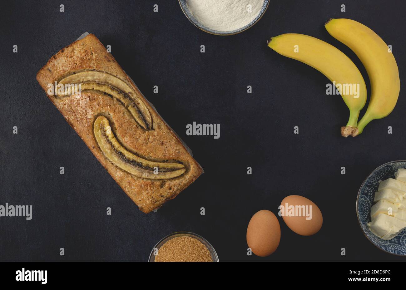 Hausgemachte Bananennuss Brot Laib isoliert auf dem dunklen Hintergrund. Zutaten für Bananenbrot. Draufsicht, flach liegend. Stockfoto