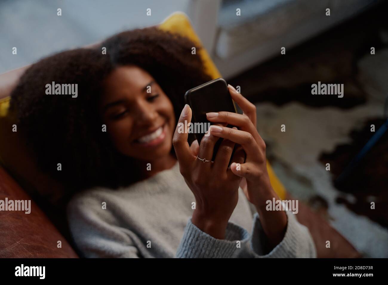 Nahaufnahme der hände afrikanischer Frau, die das Handy im Liegen halten Tisch Stockfoto
