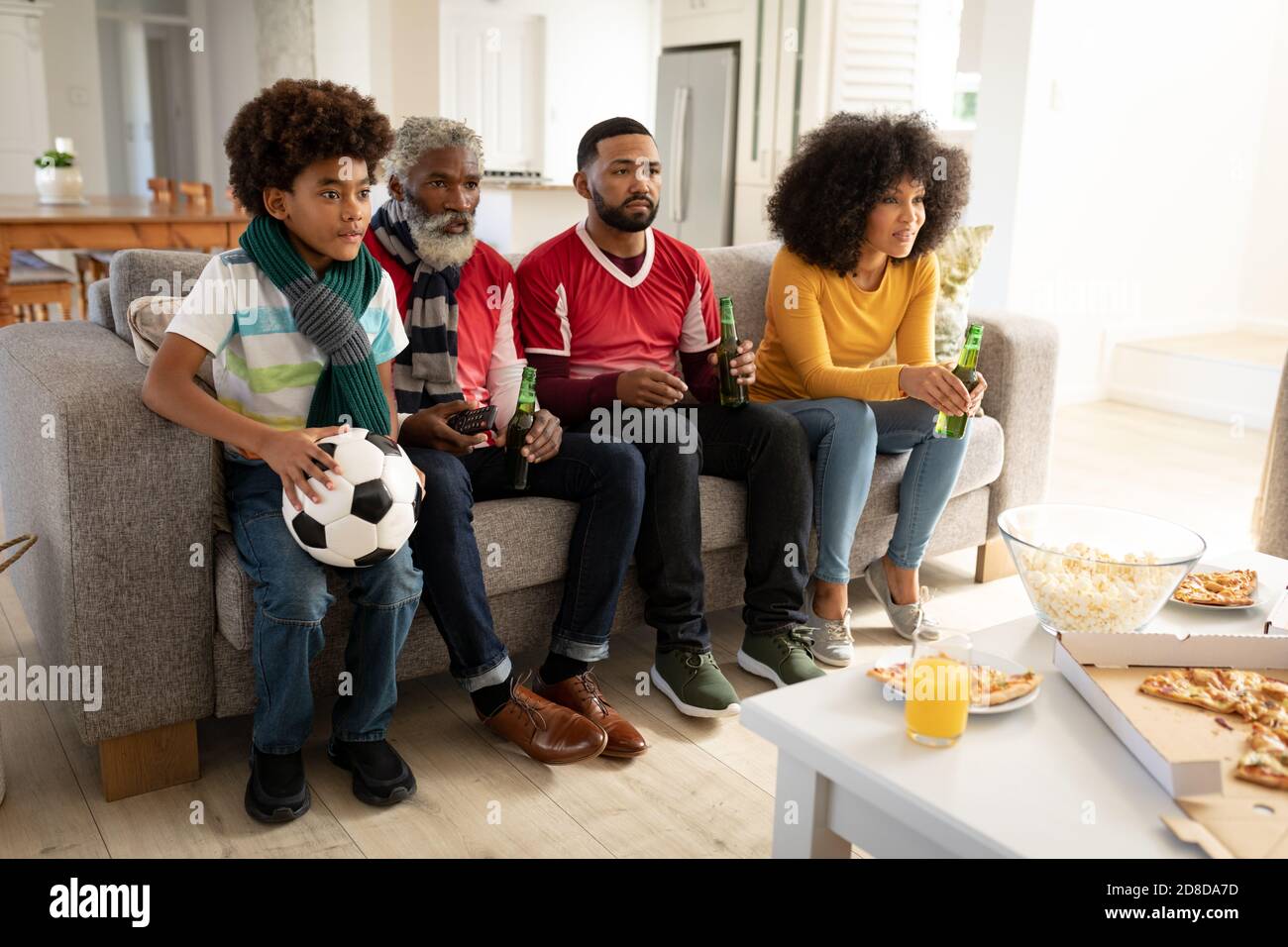 Familie mit mehreren Generationen, die zu Hause Sport im Fernsehen sieht Stockfoto