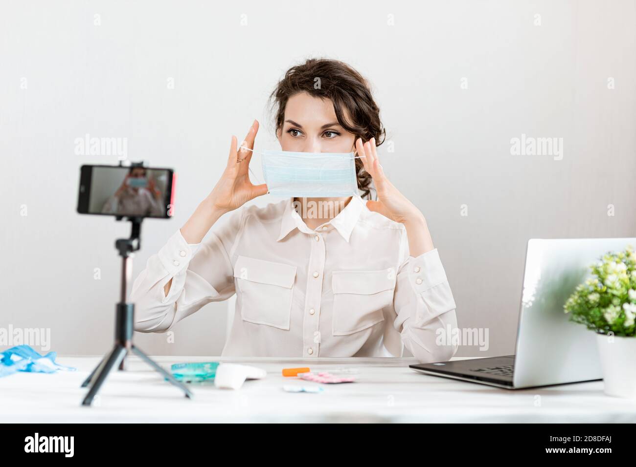 Influencer Girl Blogger in medizinische Maske spricht über Coronavirus. Frau Aufnahme Video Blog erzählt, wie man sich vor 2019-NCoV zu schützen. Bloger spricht Stockfoto