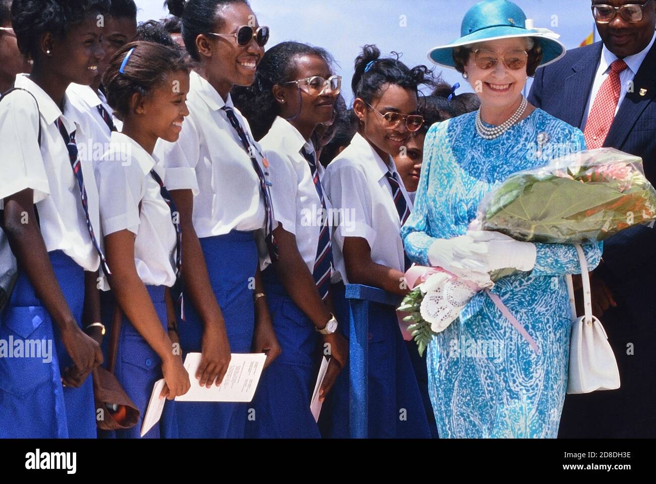 Eine Reihe lokaler Studenten und Schüler grüßen eine lächelnde Königliche Hoheit Königin Elisabeth II. Bei ihrem Besuch im Queen's College. Die Königin war bei ihrem letzten Besuch auf der Karibikinsel Barbados. März 1989. Stockfoto