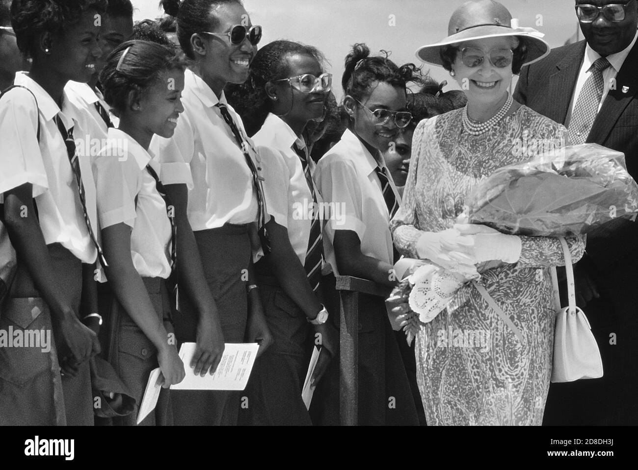 Eine Reihe lokaler Studenten und Schüler grüßen eine lächelnde Königliche Hoheit Königin Elisabeth II. Bei ihrem Besuch im Queen's College. Die Königin war bei ihrem letzten Besuch auf der Karibikinsel Barbados. März 1989. Stockfoto