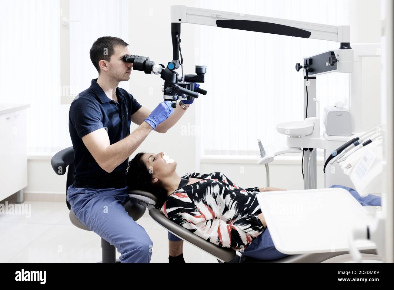 Zahnarzt arbeitet an weiblichen Patienten, mit Zahnmikroskop Stockfoto