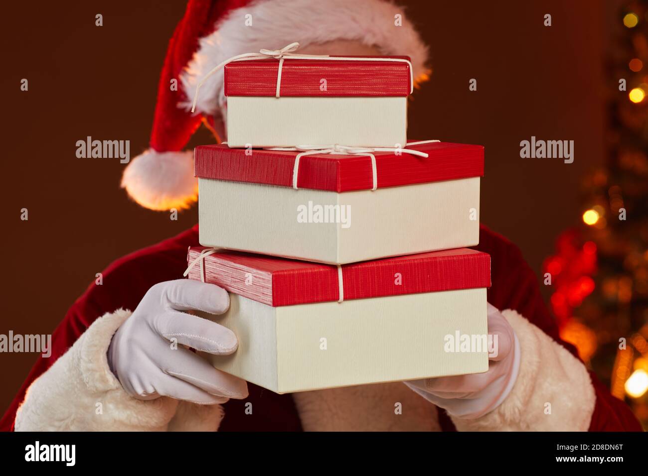 Santa hält Stapel von Geschenk-Boxen vor seinem Gesicht er bringt sie in den Urlaub Stockfoto