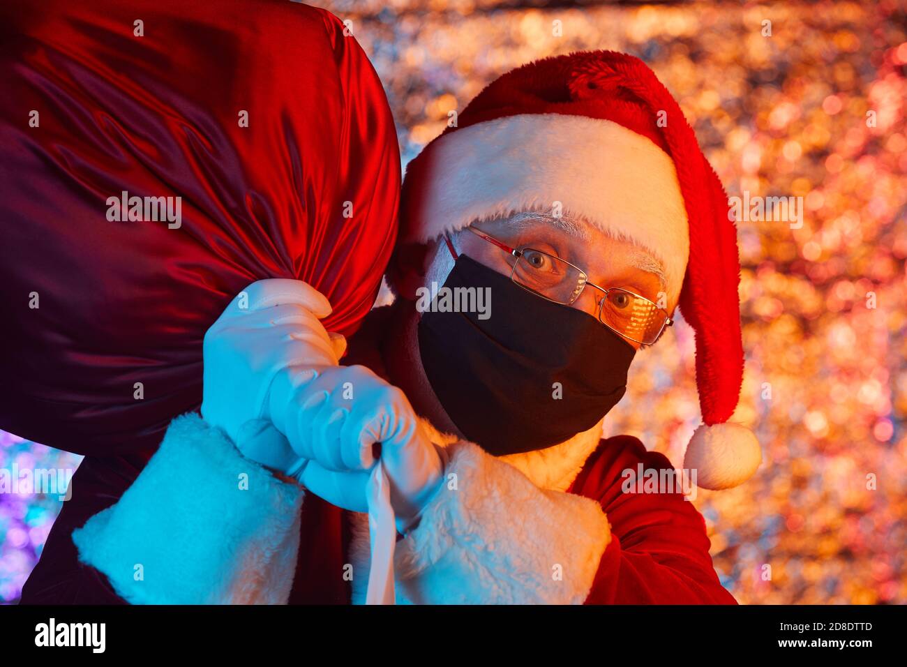 Porträt des Weihnachtsmannes in Schutzmaske trägt große schwere Tasche für Weihnachtsfeier Stockfoto