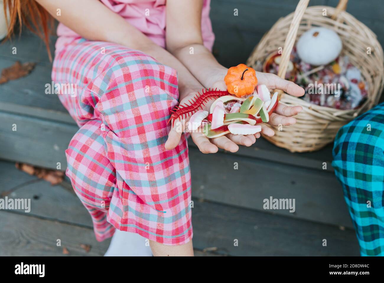 Kinder ein Junge und ein Mädchen im Pyjama teilen Süßigkeiten Und Spaß auf der Veranda des Hinterhofs eingerichtet Mit Kürbissen im Herbst Stockfoto