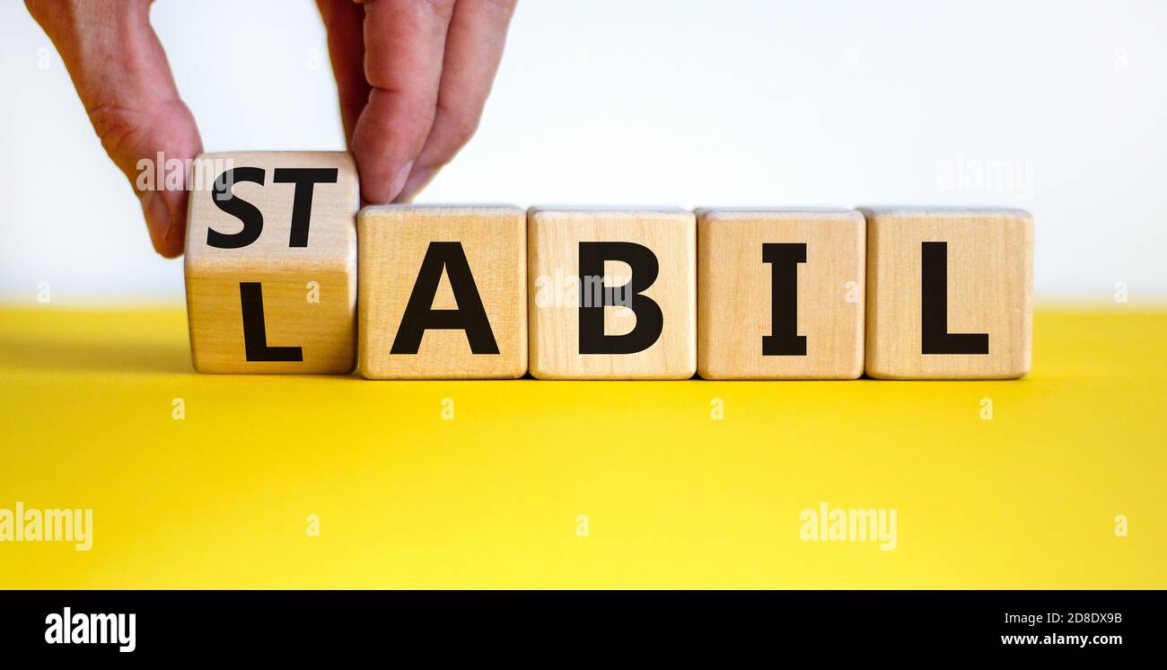 Hand dreht einen Würfel und ändert das deutsche Wort labil - instabile im  Englischen zu stabil - stabil im Englischen. Schöner gelber Tisch, weißer  Hintergrund Stockfotografie - Alamy