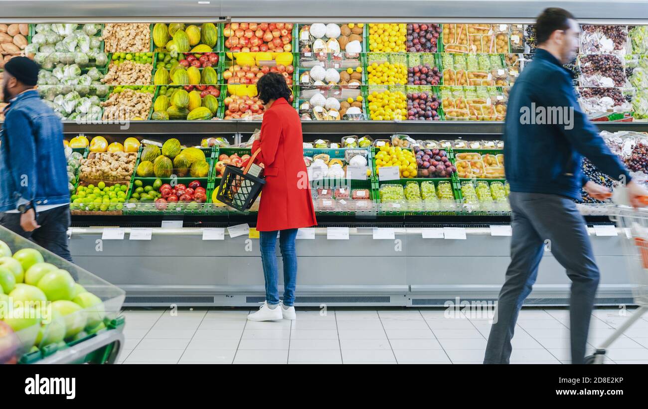 Im Supermarkt: Frau wählt Bio-Früchte in der Frischwarenabteilung des Stores. Sie holt Cantaloupe ab und legt sie in ihr Shopping Stockfoto