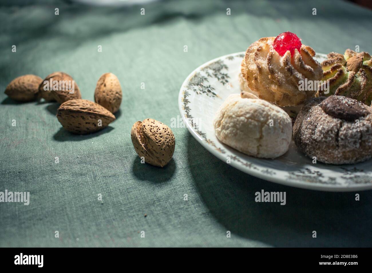 Typisch sizilianisches Gebäck: Eine Untertasse mit bunten Mandelgebäck mit kandierten Kirschen und einigen Mandeln in Schale auf dem Tisch Stockfoto