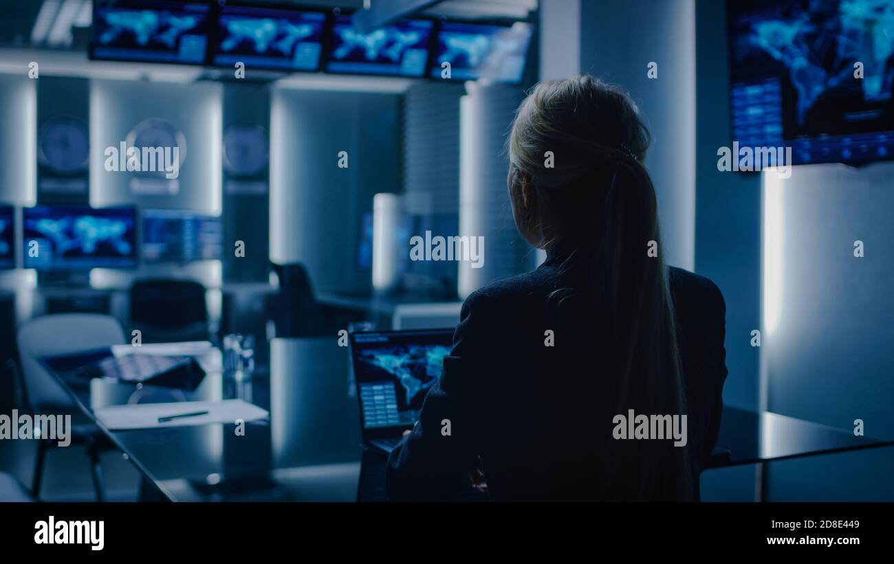 Weibliche Spezialagentin arbeitet auf einem Laptop im Hintergrund Spezialagent im Überwachungsraum spricht mit Militärmann. Im Bereich Hintergrund ausgelastet Stockfoto