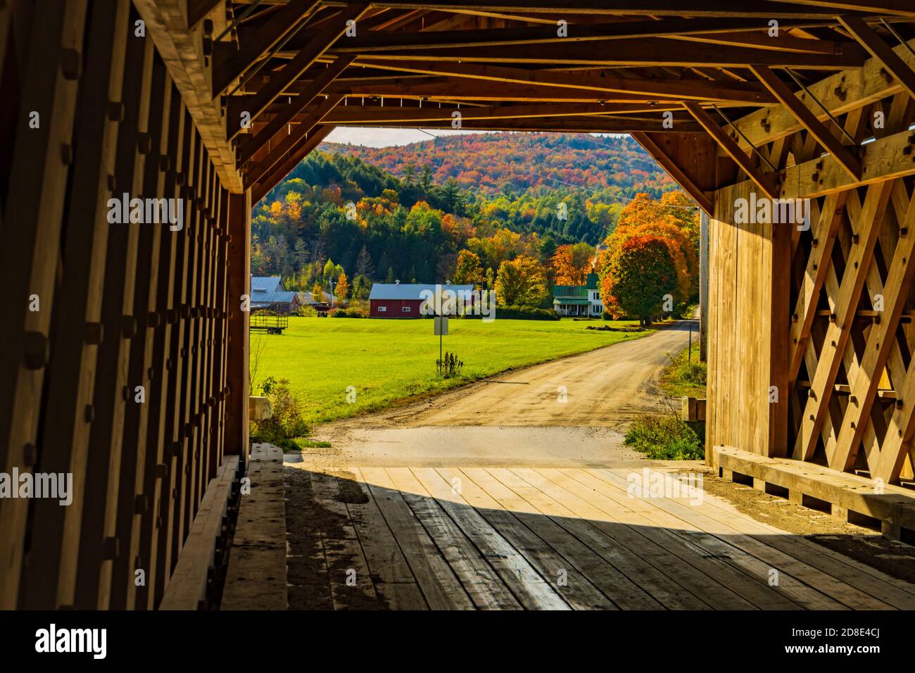 Blick aus dem Inneren eines historischen New England bedeckt Brücke auf einem Bauernhof und Hügel im Herbst bedeckt Laubfarbener Baum Stockfoto