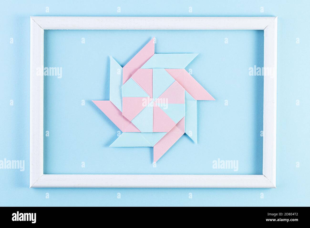 Origami-Stern. Mit quadratischen Blatt Papier und weißem Holzrahmen. Farbenfrohe Papierhandarbeiten. Stockfoto