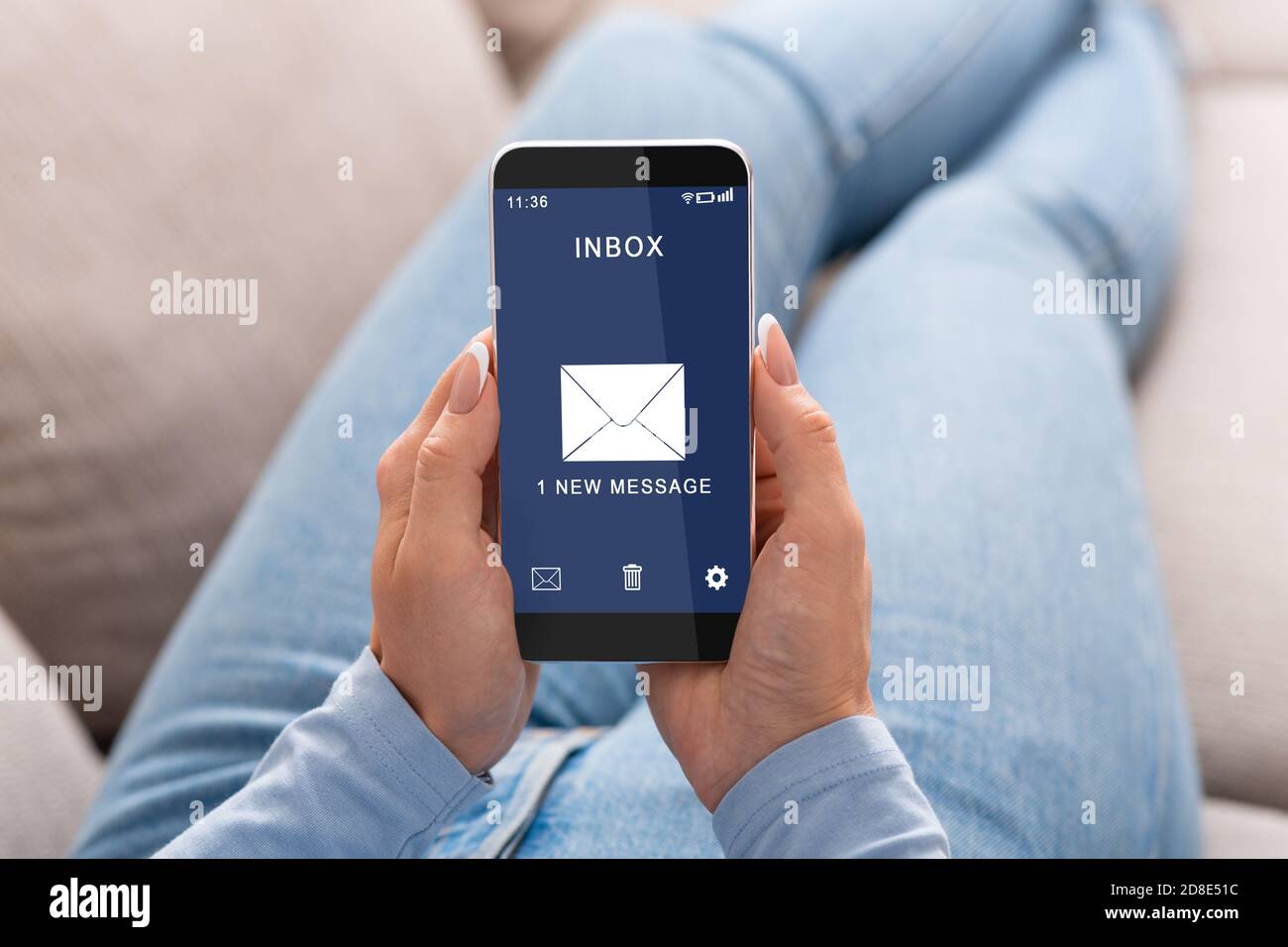 Frau liest E-Mail-Nachricht auf Smartphone sitzen auf Couch Indoor Stockfoto