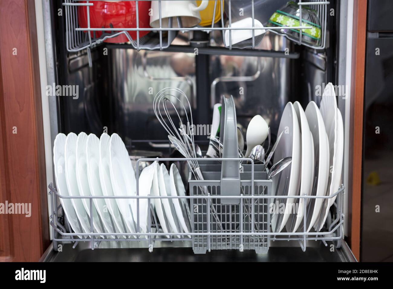 Vorderansicht der automatischen Spülmaschine voll beladen mit Utensilien. Stockfoto