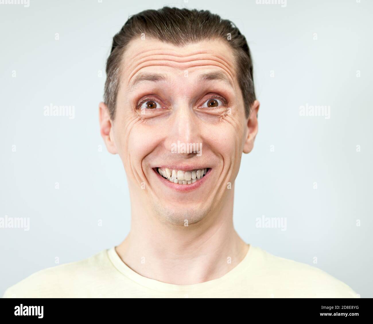 Porträt eines Mannes mit einem dummen breiten toothy Lächeln, grauer Hintergrund, Emotionen-Serie. Stockfoto