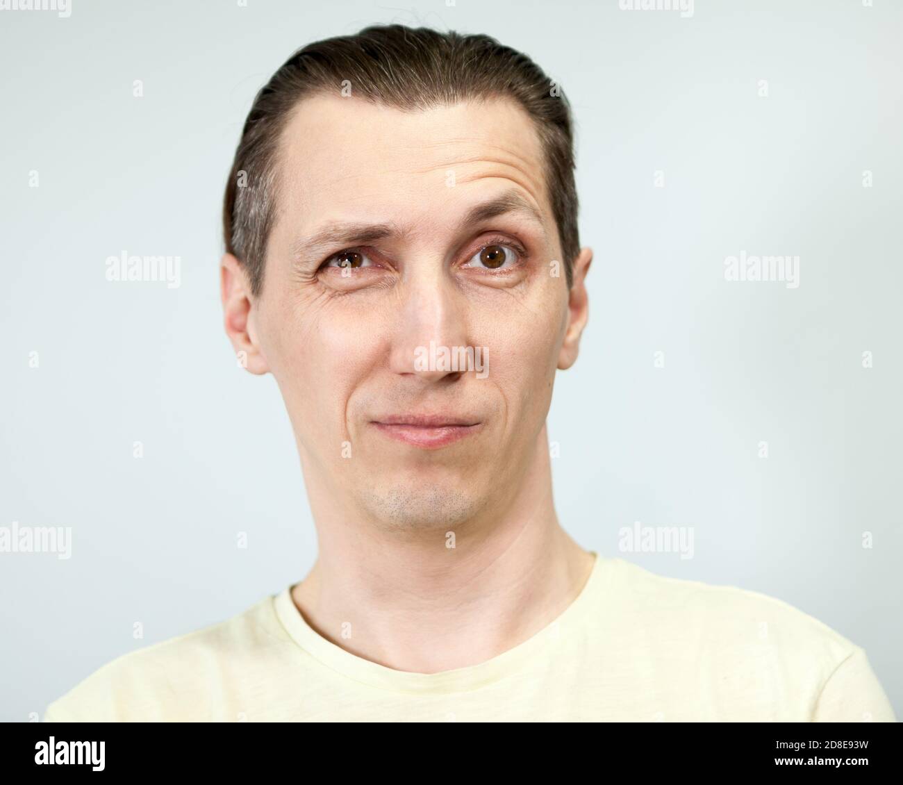 Überrascht Gesichtsausdruck mit angehoben Augenbraue in einem erwachsenen Mann, grauer Hintergrund, Emotionen Serie. Stockfoto