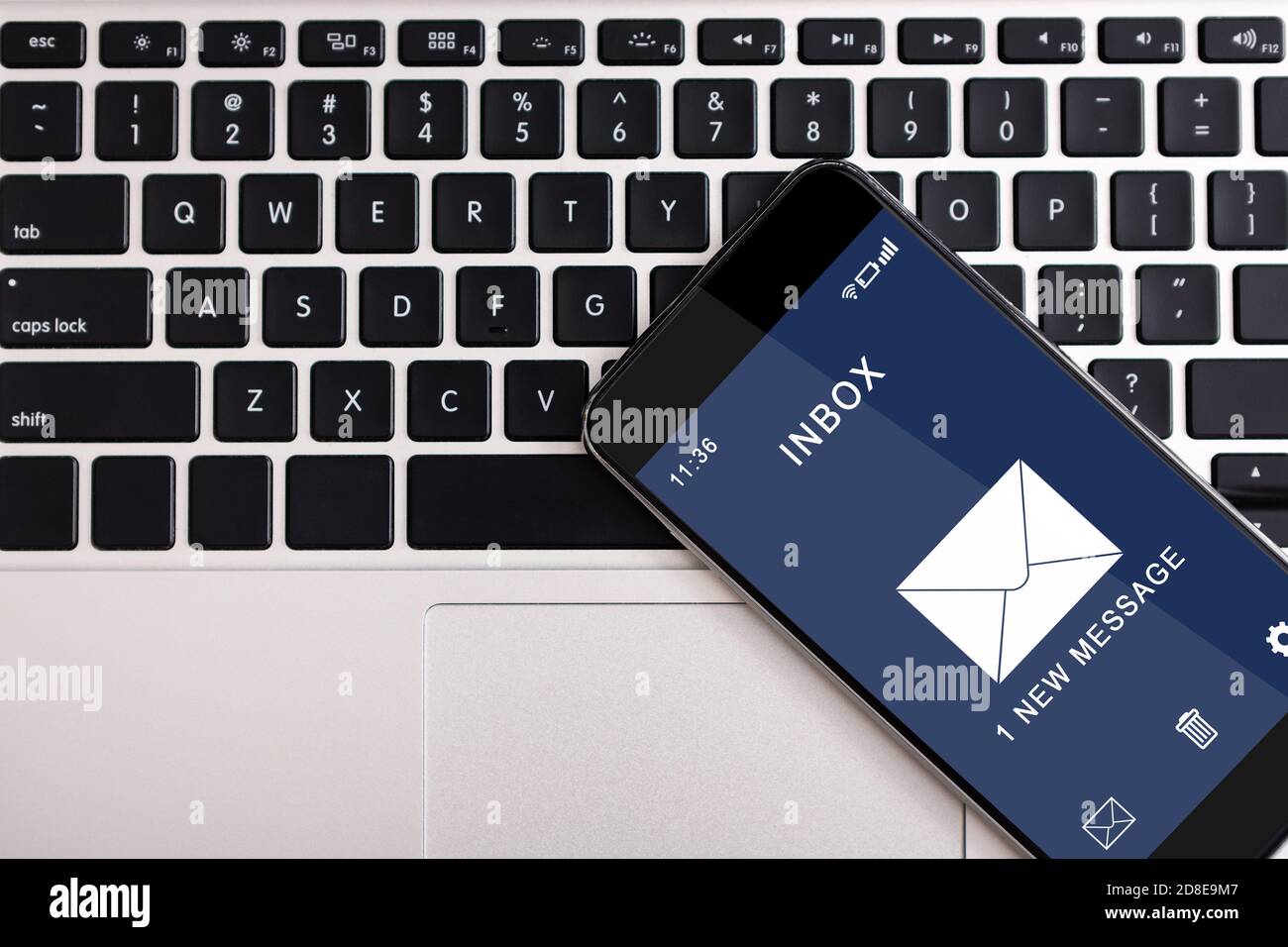 Smartphone mit Benachrichtigung über neue E-Mail-Nachrichten auf der Computertastatur Stockfoto