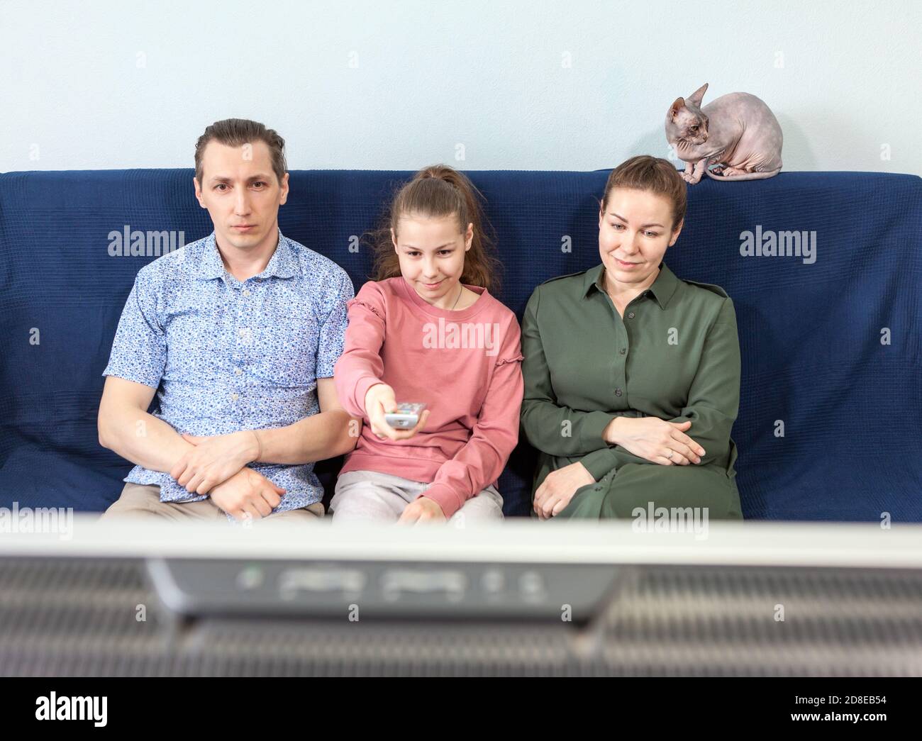 Ruhige junge Familie mit Teenager-Kind entspannen auf einer bequemen Couch im Wohnzimmer beobachten, genießen alle Tage der Woche zu Hause Stockfoto