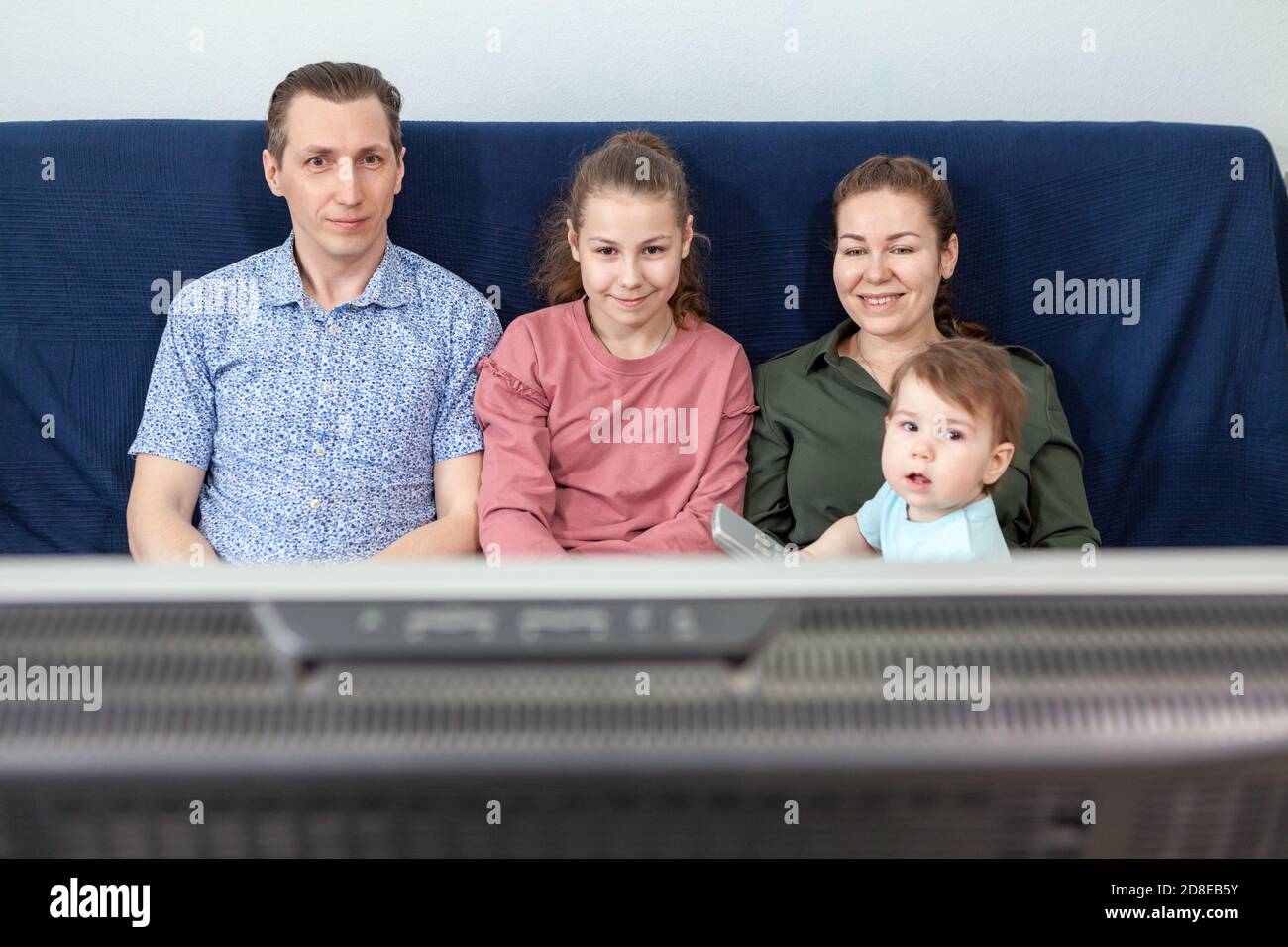 Vier Personen Familie Fernsehen-Set, während auf dem Sofa im Wohnzimmer sitzen, zu Hause bleiben Stockfoto