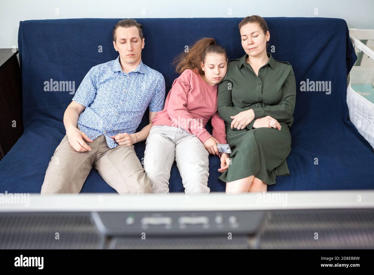 Müde drei Menschen Familie schlafen während Fernsehen im Wohnzimmer, junge Eltern mit ihrer Tochter im Teenageralter Stockfoto