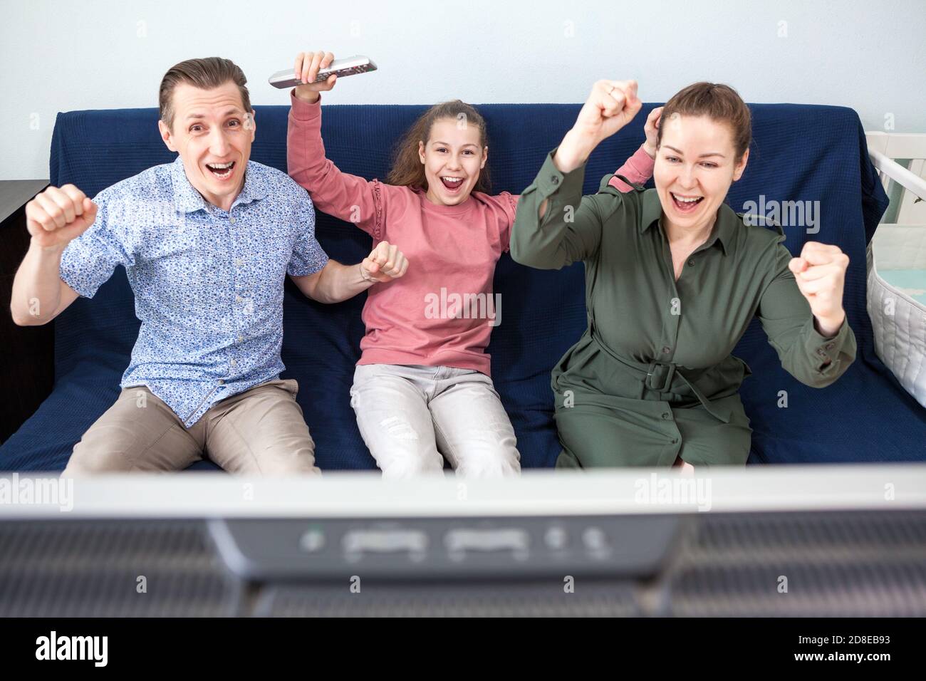 Kaukasische Familie schaut einen Fußball-Moment auf dem Fernseher, feiert ein Ziel, sitzt auf der Couch im Wohnzimmer Stockfoto