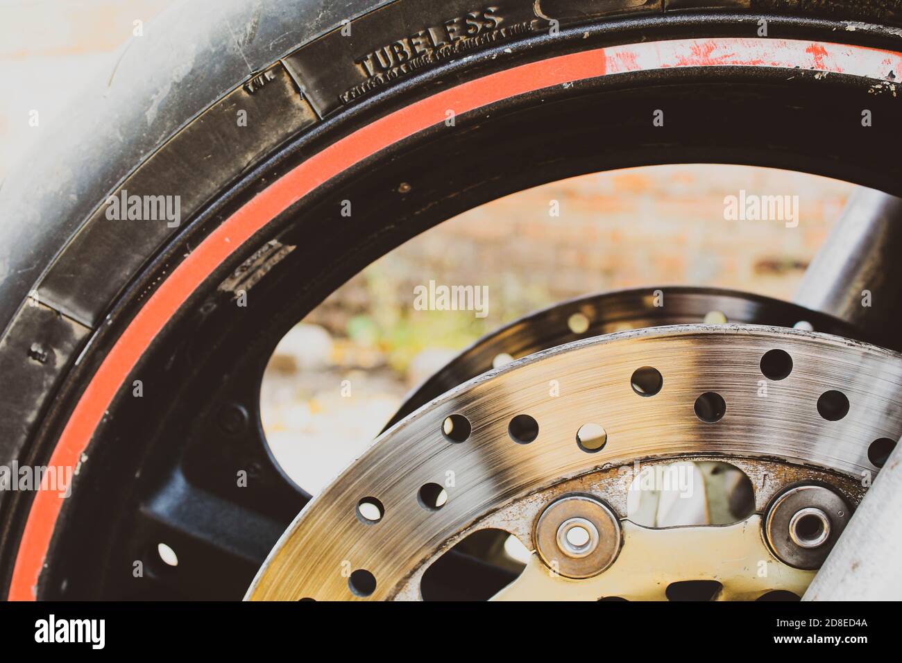 Motorrad-Rad und Bremsscheibe Nahaufnahme. Schwarzer Reifen mit rotem Streifen. Stockfoto