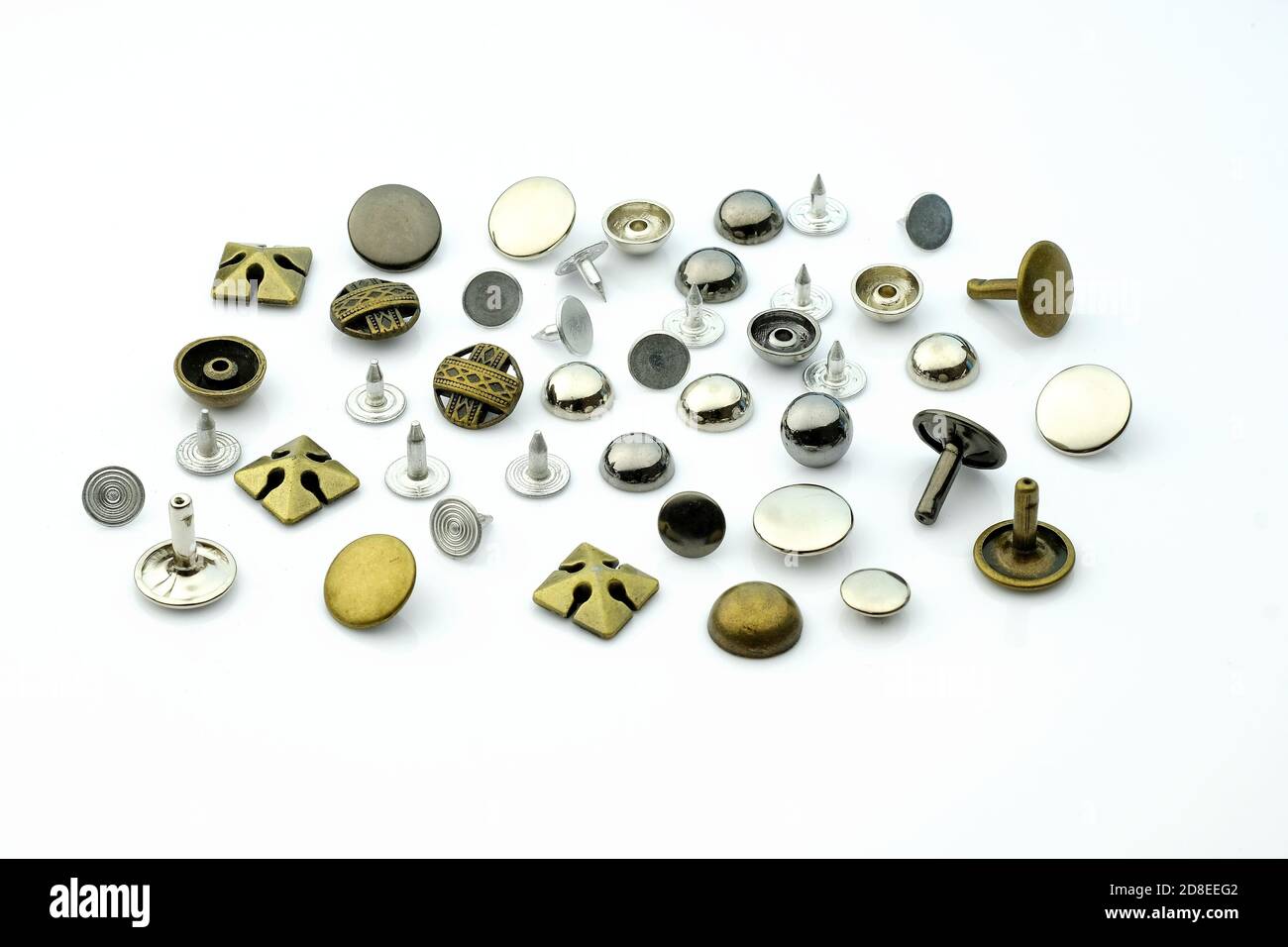 Nieten für Leder und Stoff in verschiedenen Größen und Farben auf weißem Hintergrund. Holniten für die Herstellung von Kurzwaren. Metallniete Stockfoto