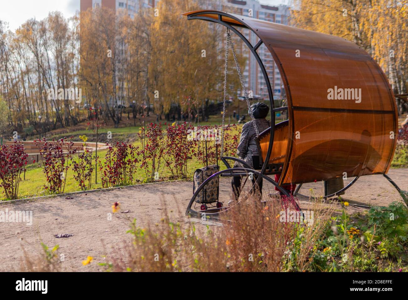 Die Urne im Park, ein Metallbehälter auf dem Rasen in der offenen Natur in der Nähe der Straße aus Steinen, Nachmittag bei sonnigem Wetter genießen Sie das Konzept. Gartenschaukeln. Stockfoto