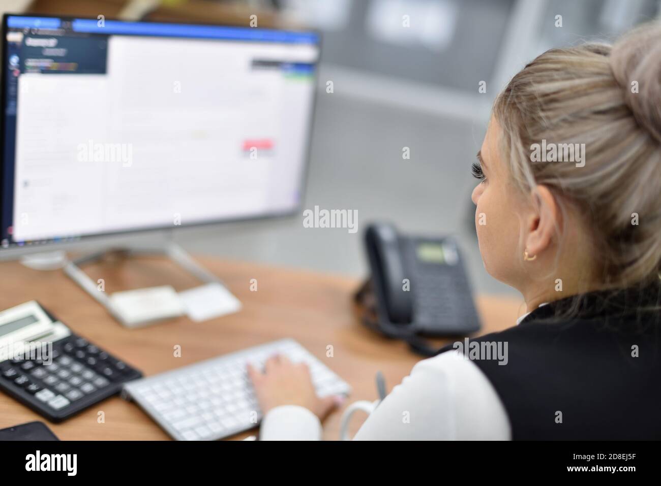 Eine Frau arbeitet in einem Büro und schaut auf die Überwachen Stockfoto