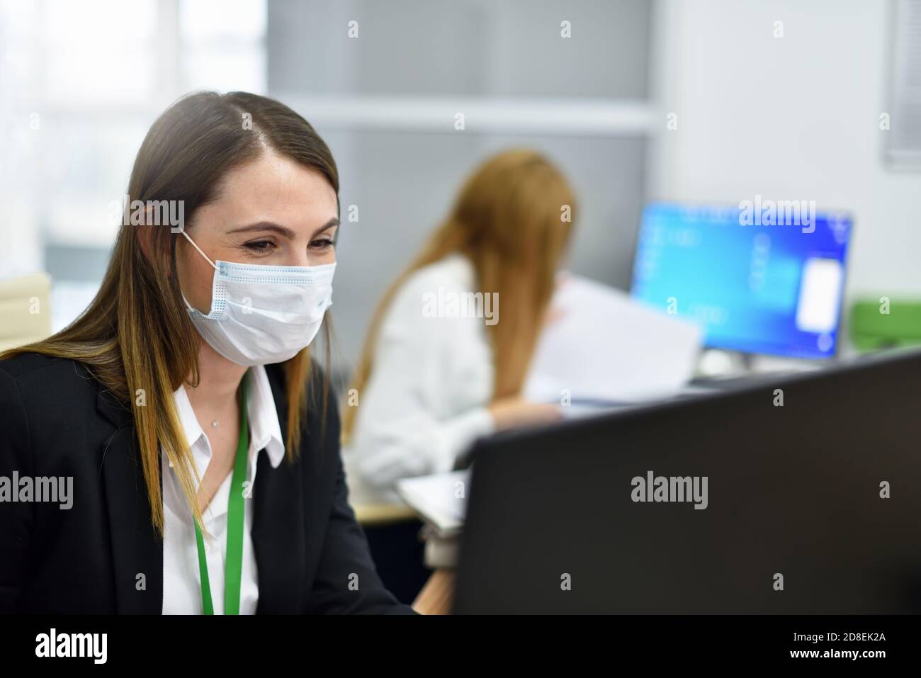 Glückliche Frau Büroleiter in Schutzmaske arbeitet am Computer Im modernen Büro Stockfoto