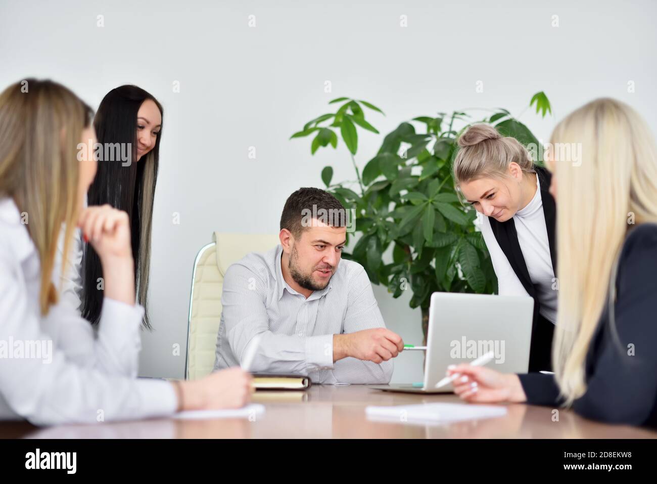 CEO bei einem Treffen mit weiblichen Mitarbeitern erklärt neue Ideen Mit einem Laptop Stockfoto