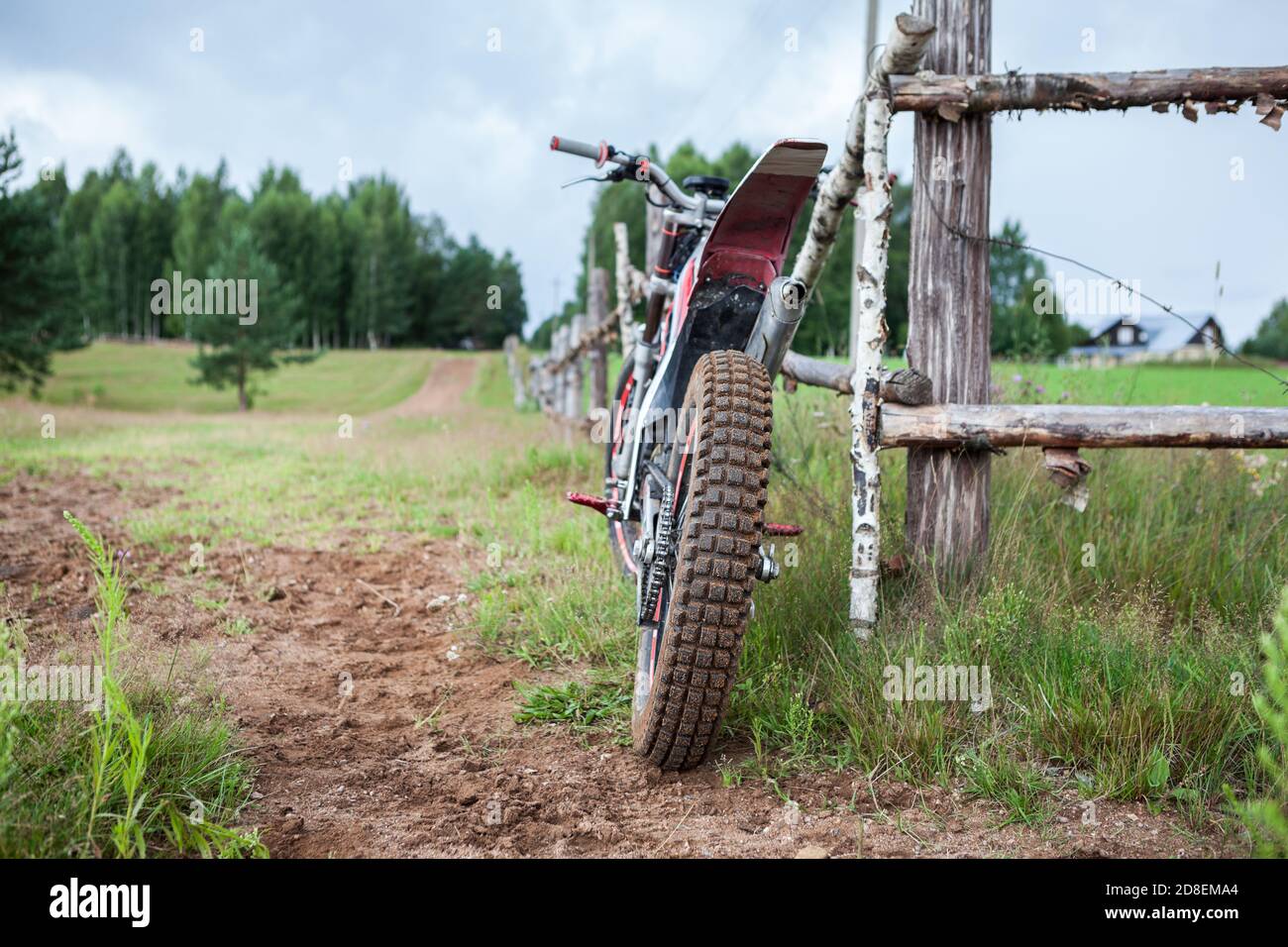 Freizeit Off-Road-Motorrad lehnt an ländlichen Holzzaun im Dorf, Rückansicht, Copyspace Stockfoto