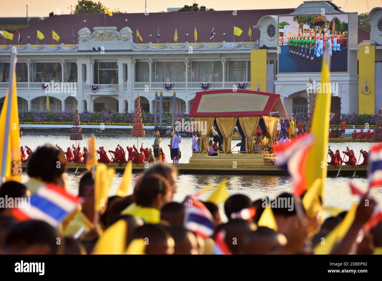 Die Thai Royal Barge Prozession, die letzte Phase der Krönung von König Rama 10 entlang Chao Phraya River, während Thai Zuschauer winken Thai Fahnen. Stockfoto