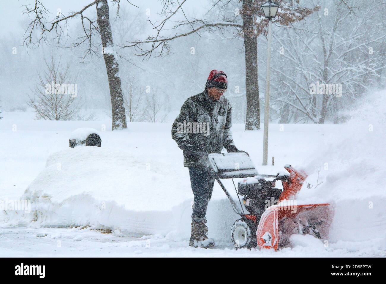 Ein älterer Bürger, Baby-Boomer, tragen Ohrenschutz und Schneeschuhe, Schnee weht die Straße in Chicago während eines winterlichen polaren Wirbel. Stockfoto