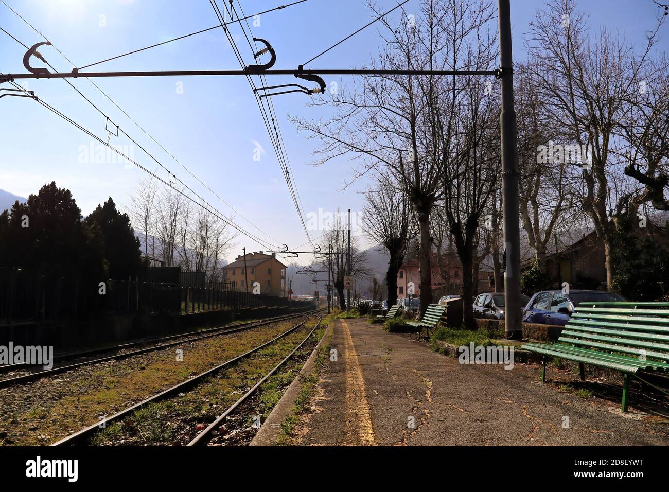 Perspektive eines leeren Bahnsteigs in einem alten Bahnhof mit Bänken und Gras, das zwischen den Gleisen gewachsen ist. Genua - Casella Bahn. Italien. Stockfoto