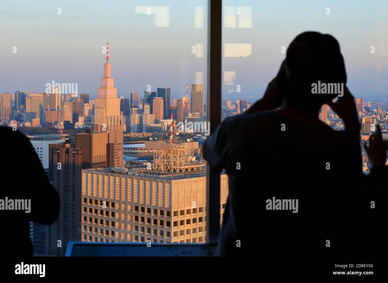 Die Silhouette eines Besuchers, der Fotos von Tokio gemacht hat Stadtbild von der Aussichtsplattform der Tokyo Metropolitan Government aus gesehen Gebäude mit NTT Docomo Yoyogi Gebäude im Vordergrund.Shinjuku.Tokyo.Japan Stockfoto