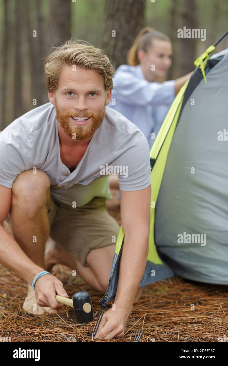 Junger Mann, der ein Zeltlager zum Campen aufsetzt Stockfoto