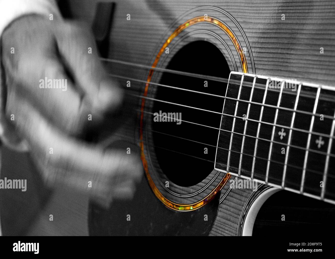 Eine Person spielt akustische Gitarre mit nur Farbe die Details rund um das Schallloch. Stockfoto