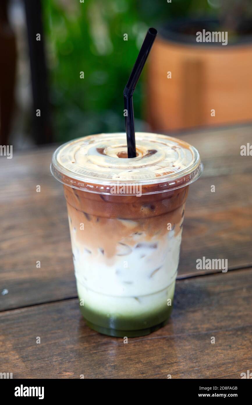 Gesundes Getränk mit grünem Tee und Milch in Schichten von Farbe auf Holztisch gemischt. Stockfoto