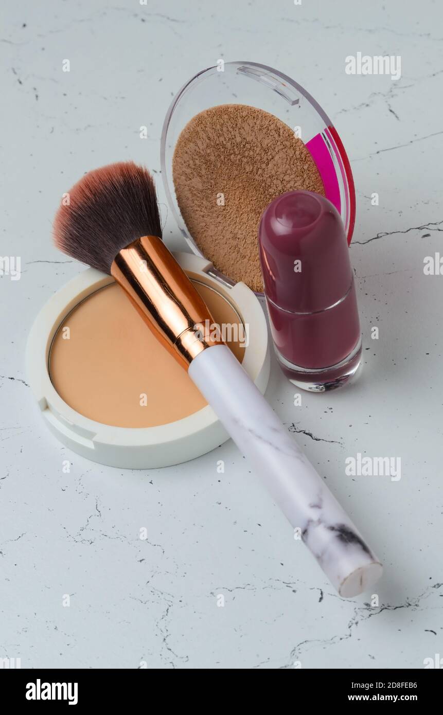 Ein alter Schminkpinsel mit Puder und Nagellack auf einer texturierten Tischoberfläche. Selektiver Fokus. Stockfoto